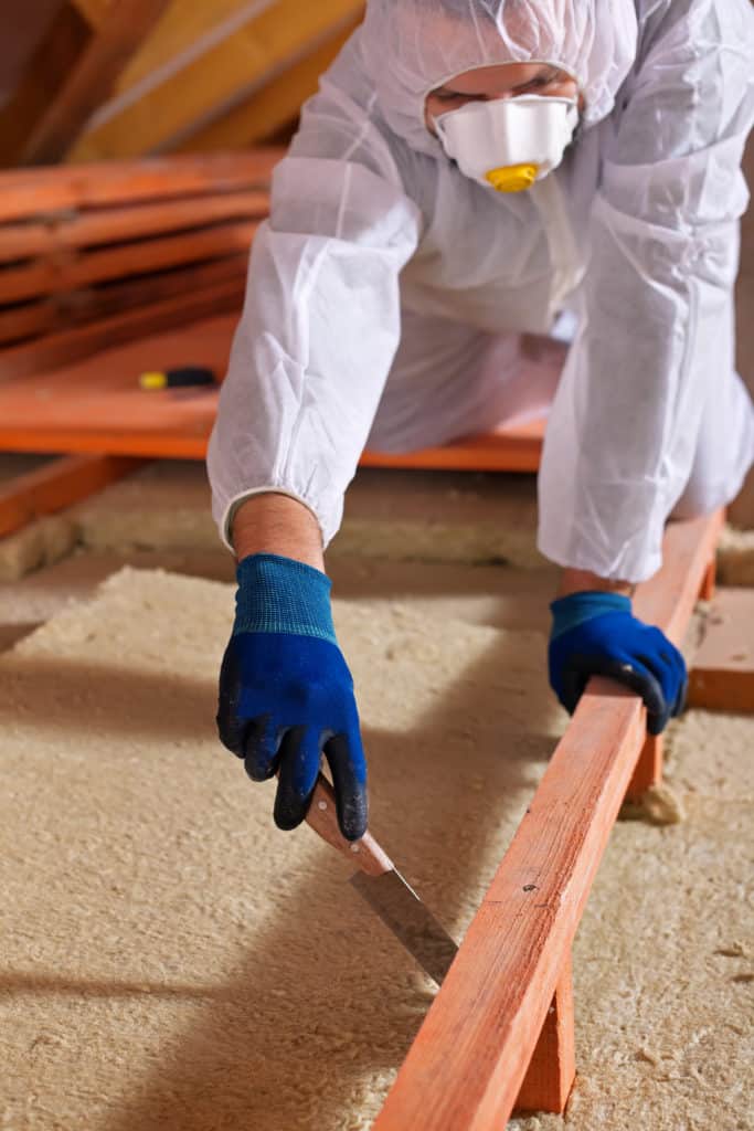 Man laying thermal insulation layer on building emissions cov laine minerale epi protection